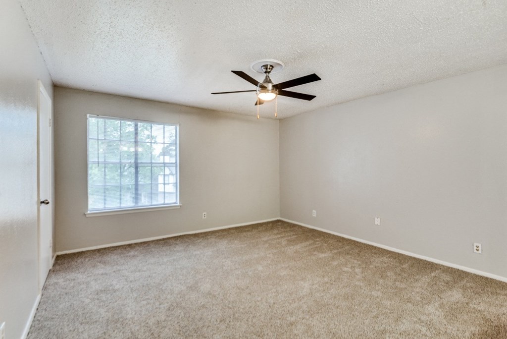 an empty living room with a ceiling fan and a window