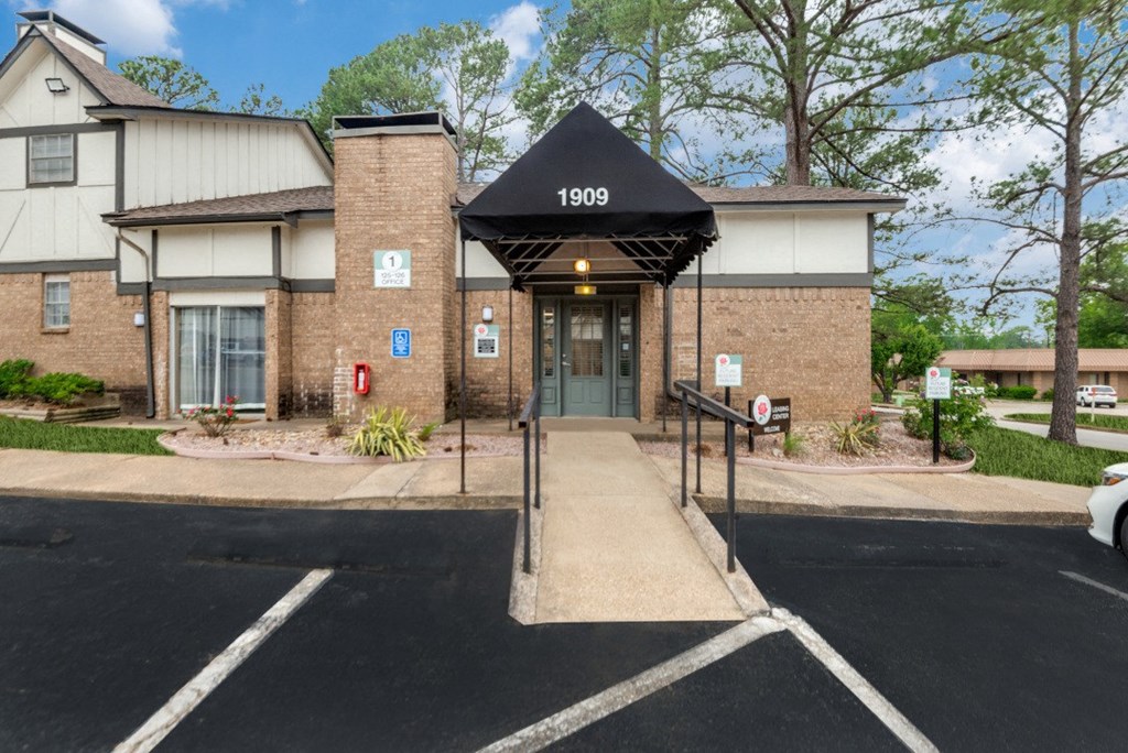 a brick building with a black awning and stairs in front of a driveway