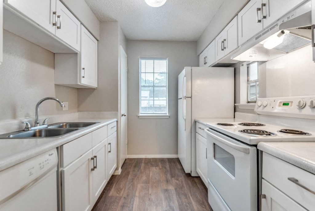 an empty kitchen with white appliances and white cabinets