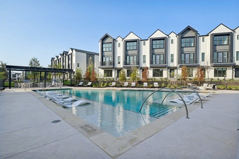 A swimming pool in front of a row of houses.