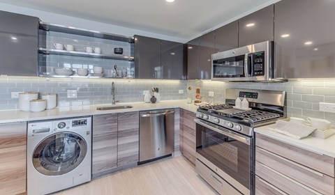 A modern kitchen with a washing machine and a microwave oven.