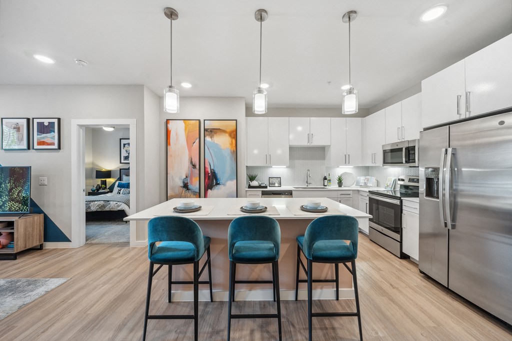 a kitchen with stainless steel appliances and an island with blue chairs