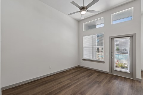 A room with a ceiling fan and a door leading to a balcony.