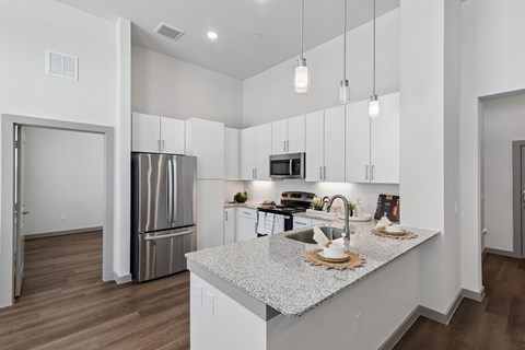 A modern kitchen with a stainless steel refrigerator and a marble countertop.