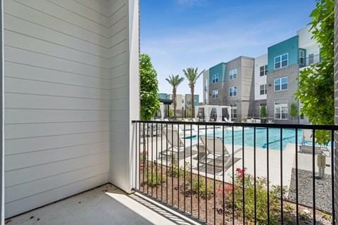A balcony with a pool and apartment buildings in the background.