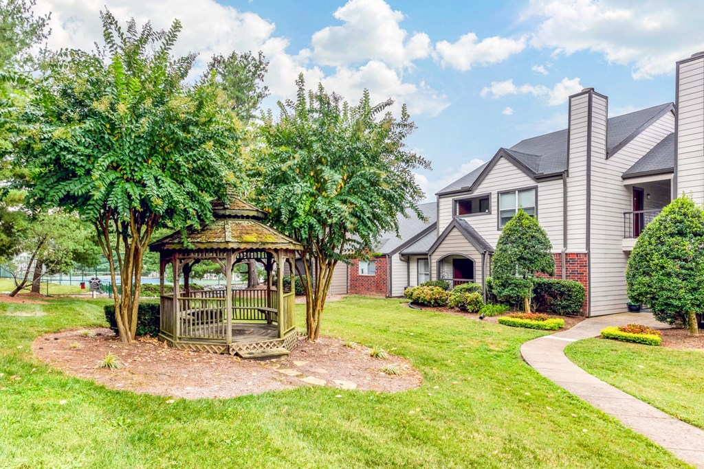 a gazebo sits in the middle of a grassy area in front of a