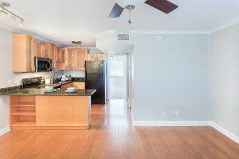 A kitchen with wooden cabinets and a black refrigerator.