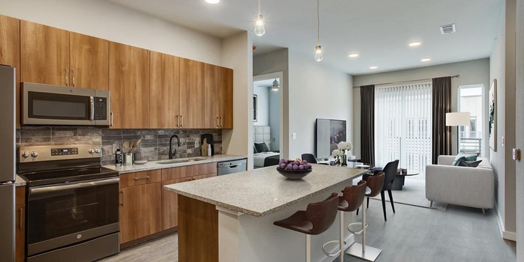 A modern kitchen with wooden cabinets and a marble countertop.