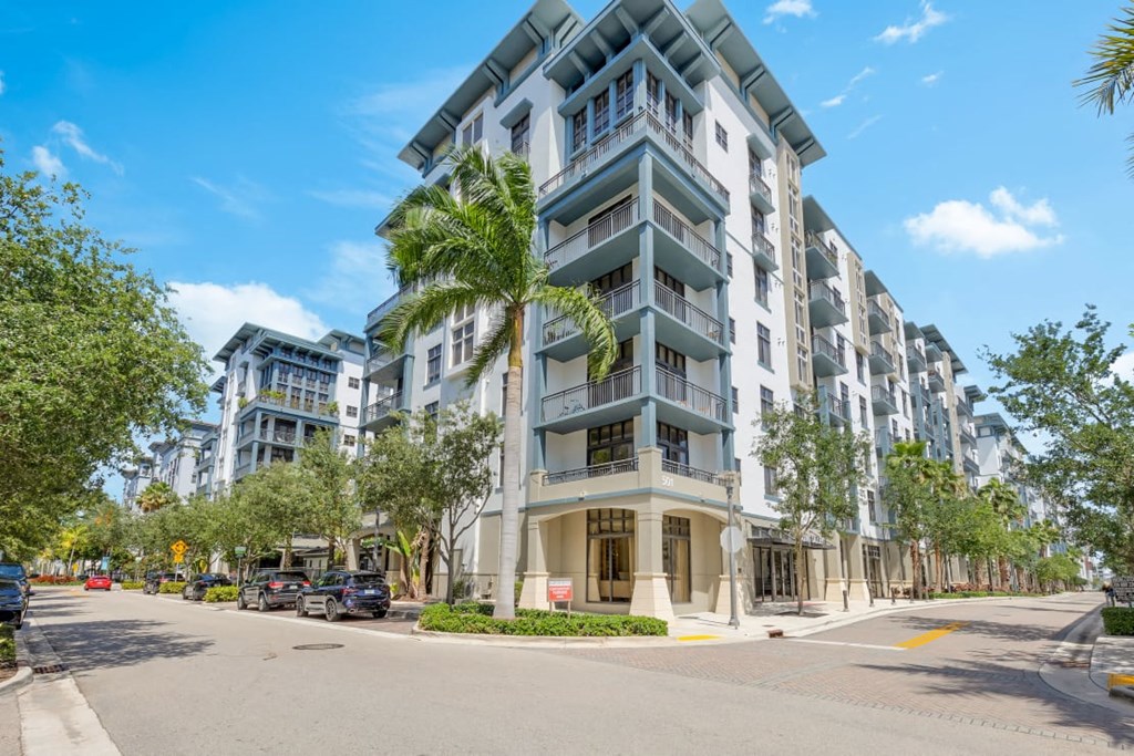 an apartment building on the corner of a street with palm trees