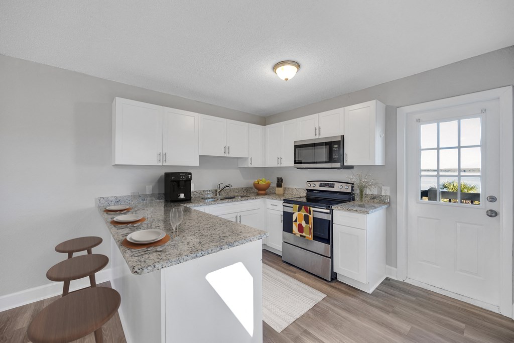 a kitchen with white cabinets and a granite counter top and a stove