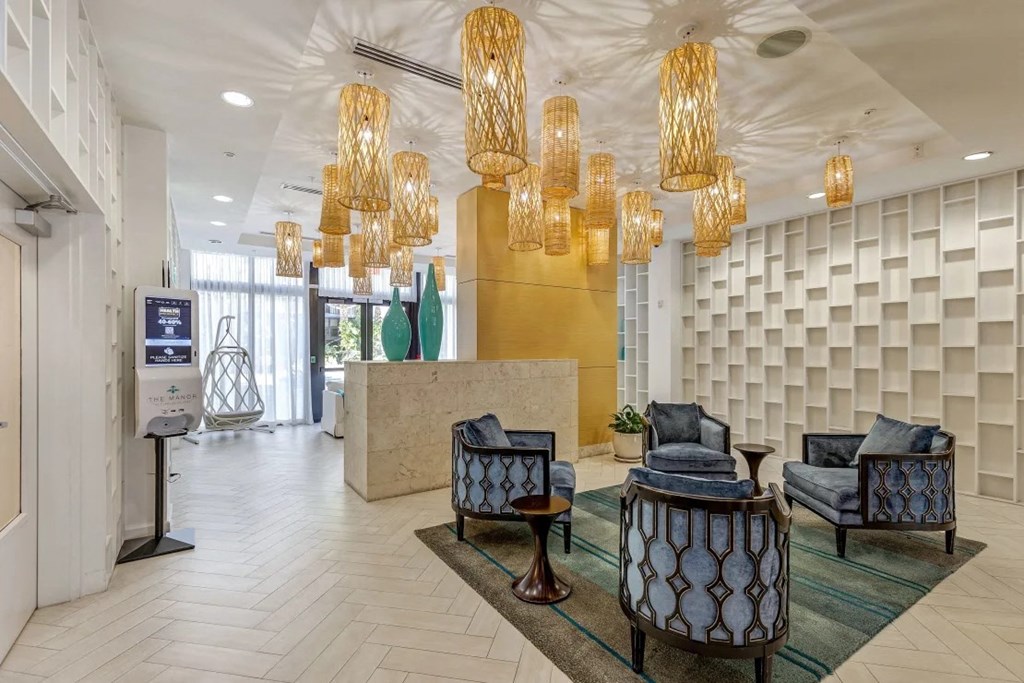 a lobby of a hotel with chairs and chandeliers