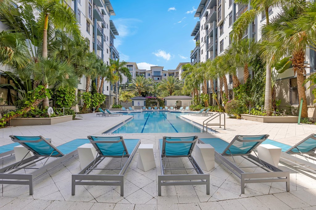 an outdoor pool with chairs and palm trees in an apartment building