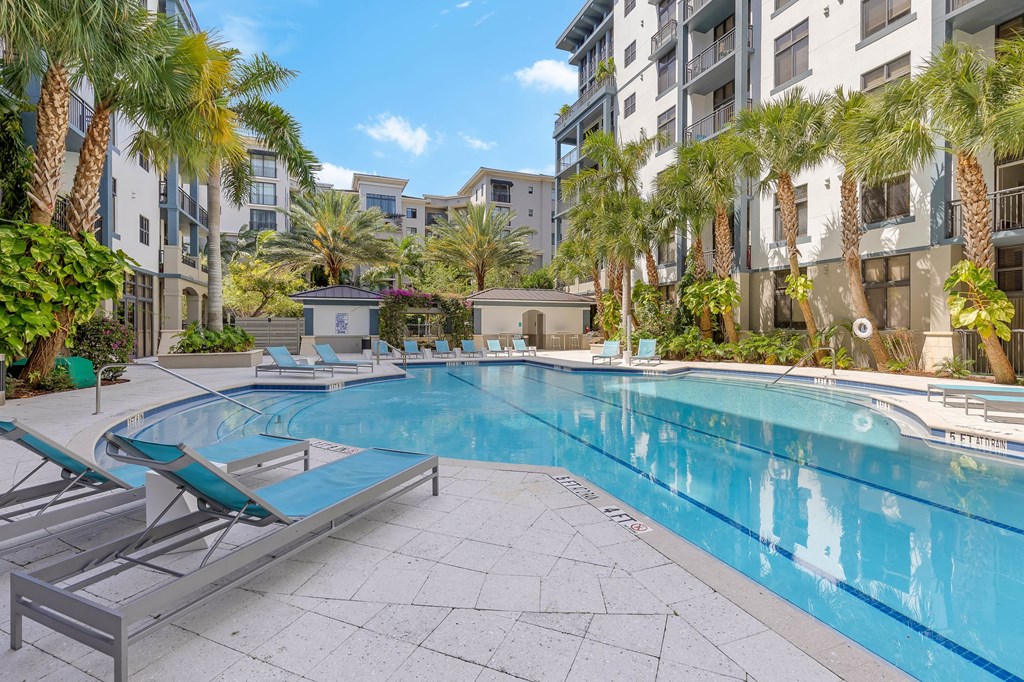 a swimming pool with palm trees in front of an apartment building