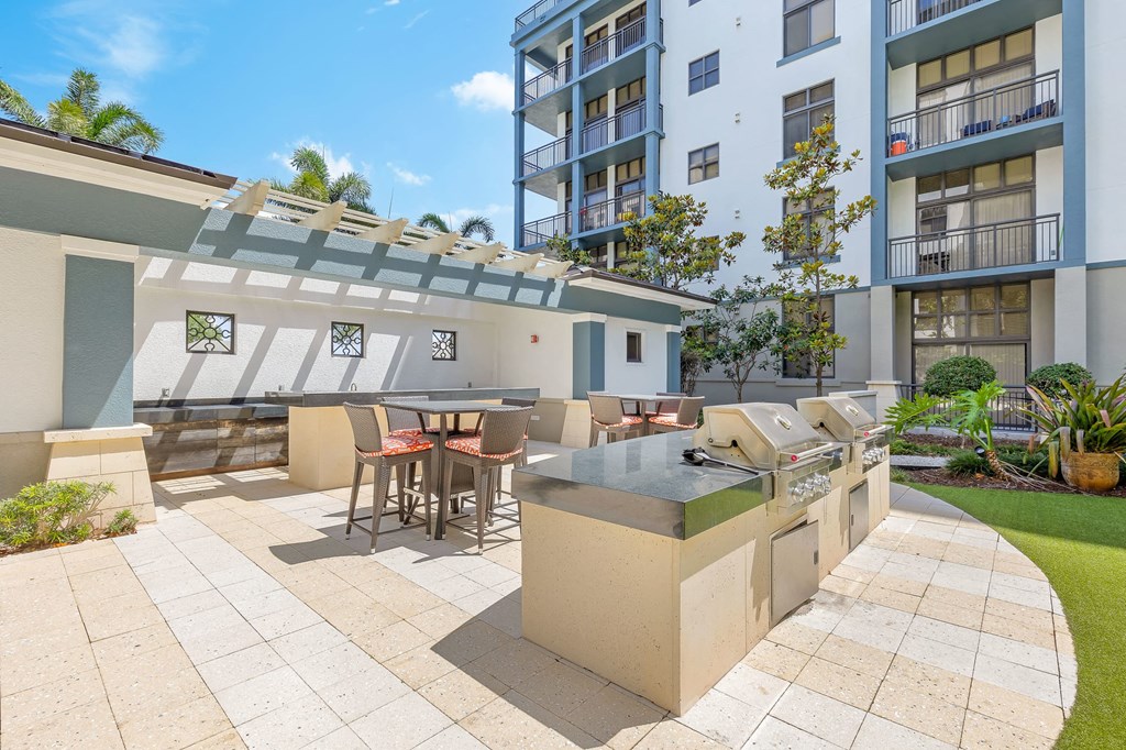 a patio with a grill and a table with chairs
