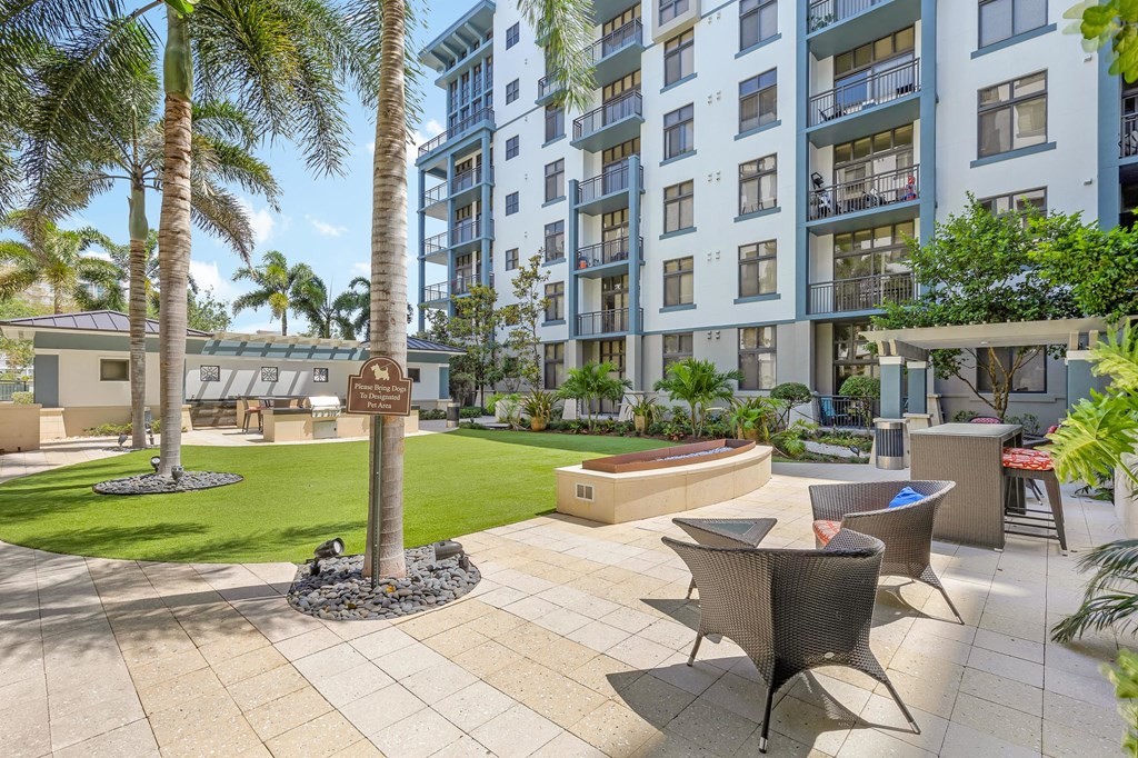 a patio with chairs and a tree in front of an apartment building