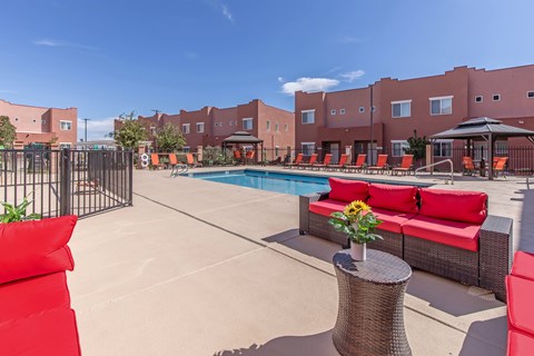 A pool area with red couches and a table with flowers on it.