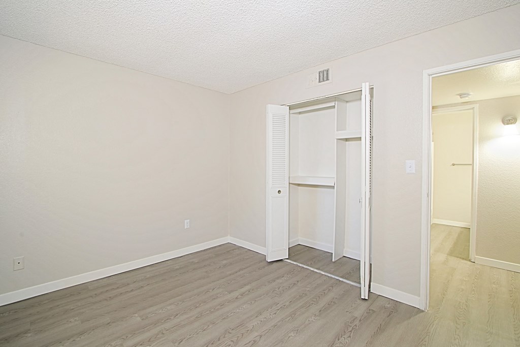 a bedroom with hardwood floors and white walls