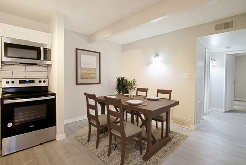 A kitchen with a table and chairs and a fridge.