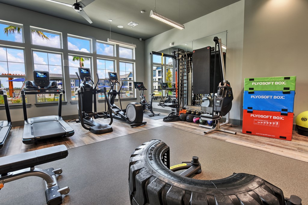 a gym with weights and cardio equipment and windows