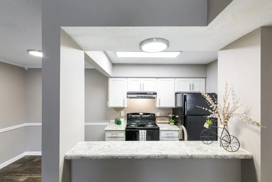 a kitchen with white cabinets and black appliances