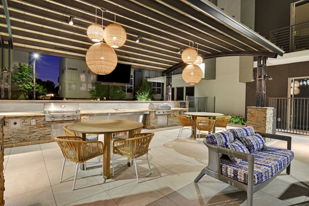 a patio with tables and chairs and an outdoor kitchen