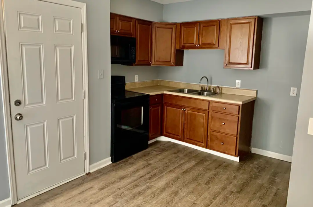 an empty kitchen with wooden cabinets and black appliances