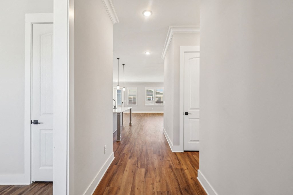 A long hallway with white walls and wood floors.