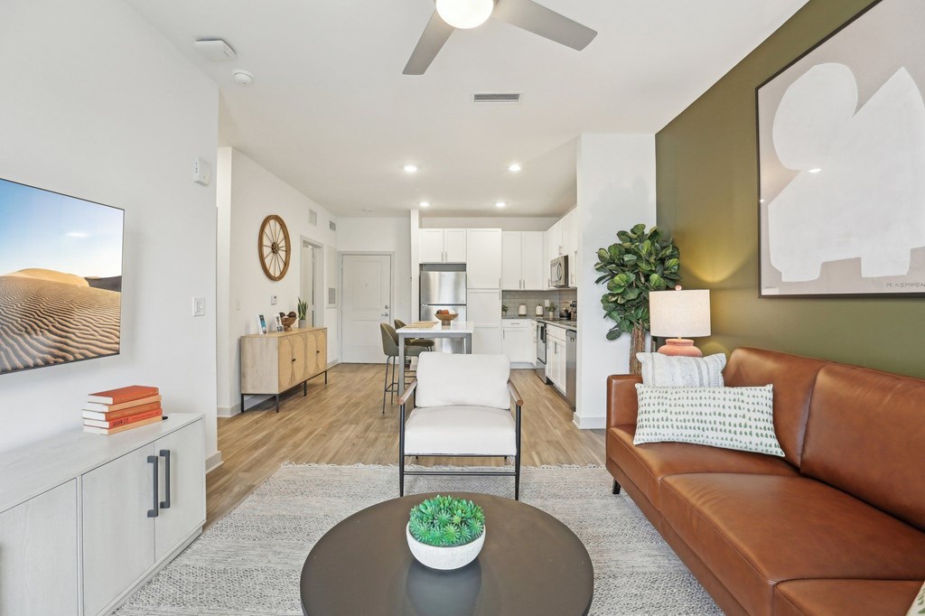 A living room with a brown couch, a coffee table, and a flat screen TV.
