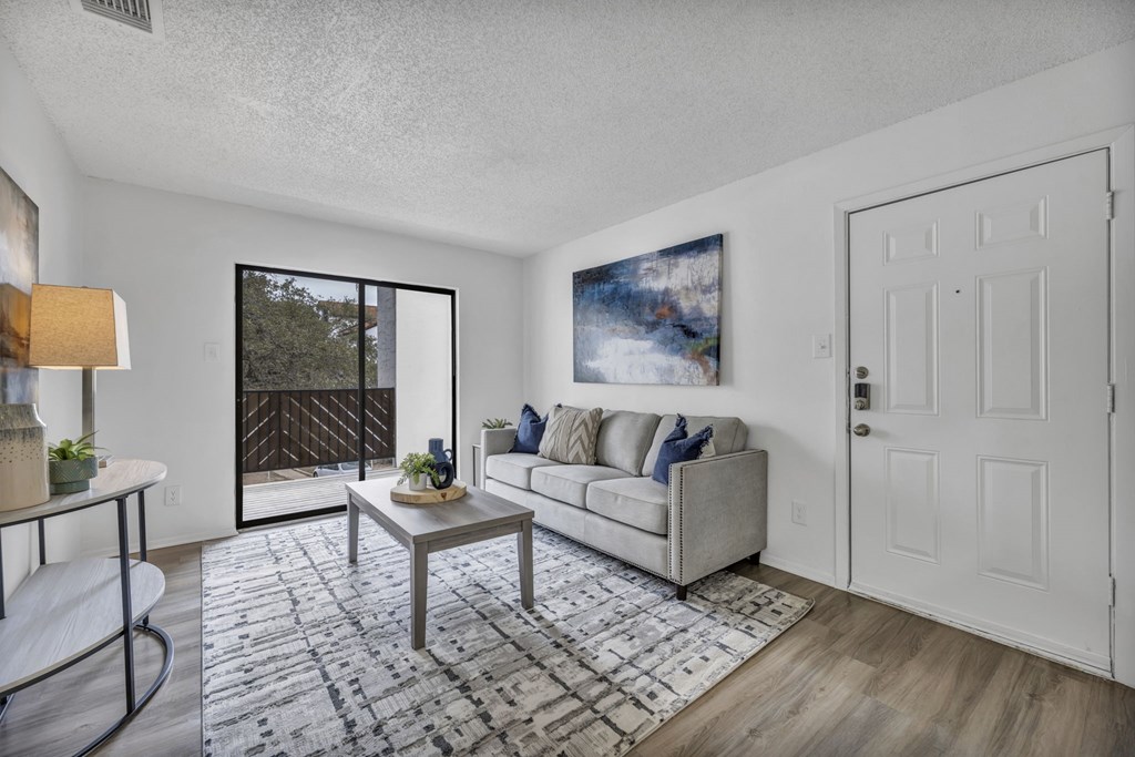 A living room with a grey couch and a painting on the wall.