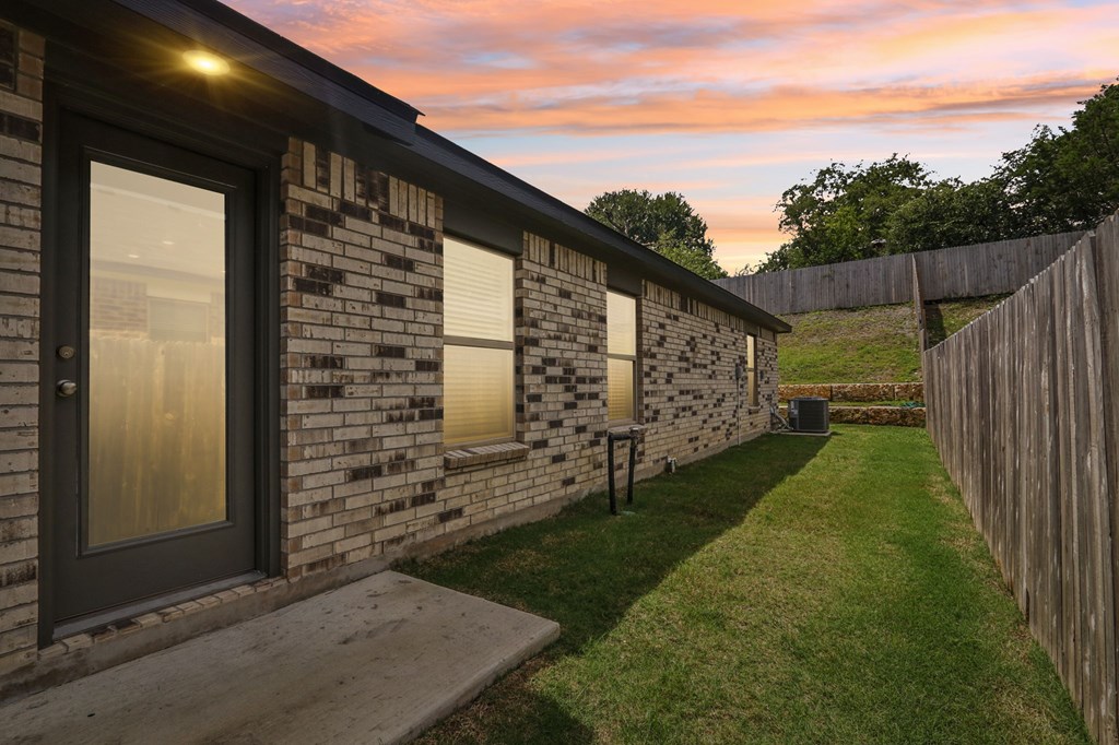 A house with a wooden fence and a green lawn.