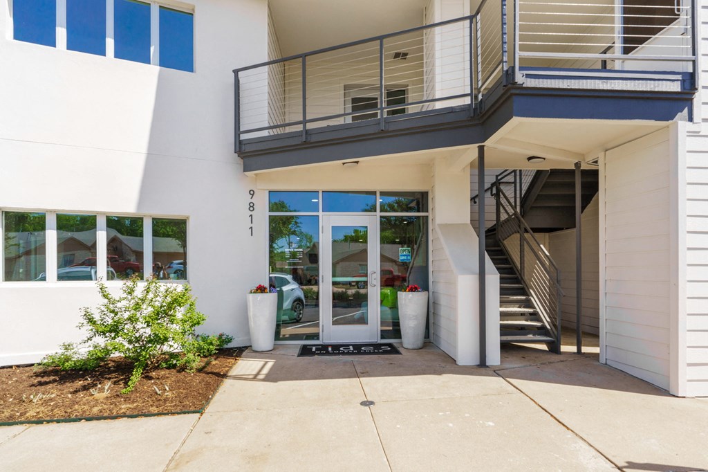 the entrance to a white building with a staircase and a glass door