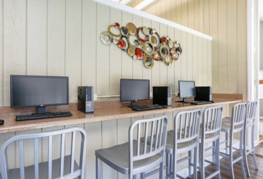 a desk with computers and chairs in a room