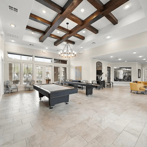A large billiard table is in the middle of a spacious room with a high ceiling and wooden beams.