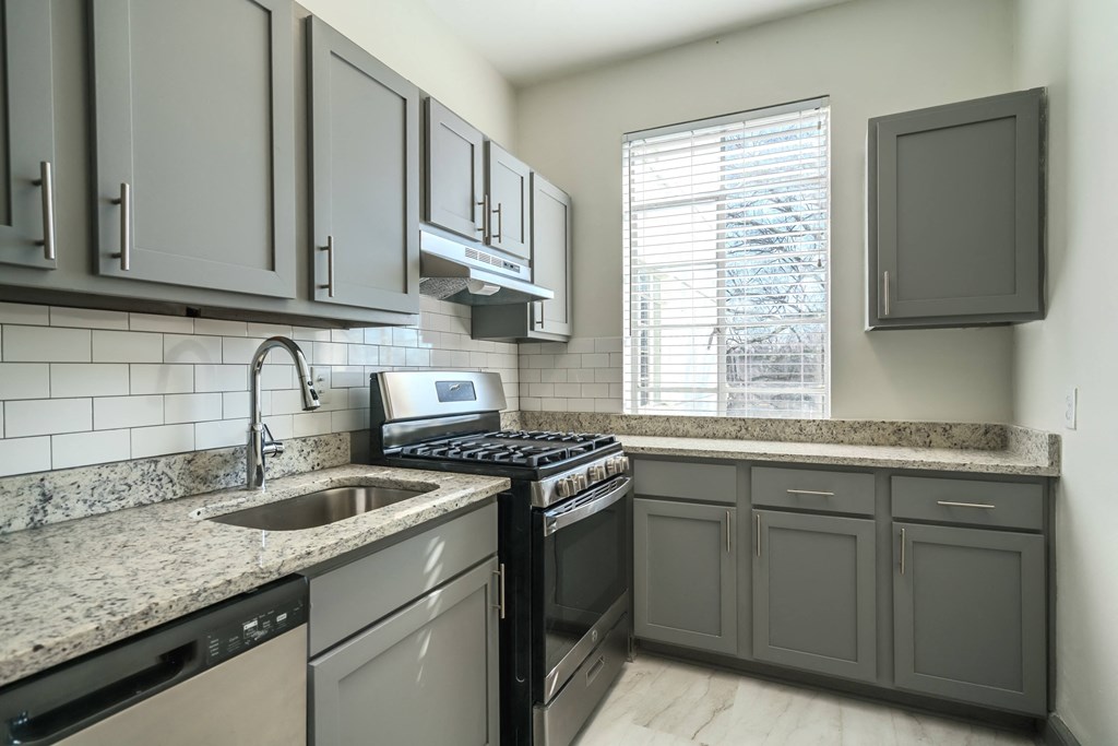 an empty kitchen with granite counter tops and black appliances