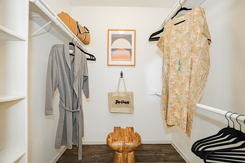 a closet with clothes hanging on the wall and a wooden chair