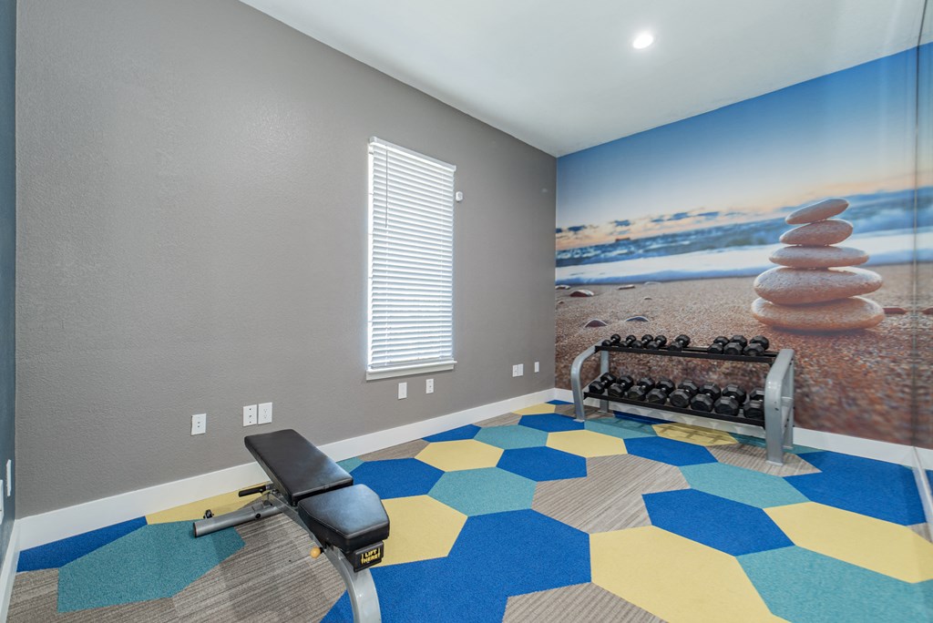 a workout room with a gym bench and a wall mural of the beach