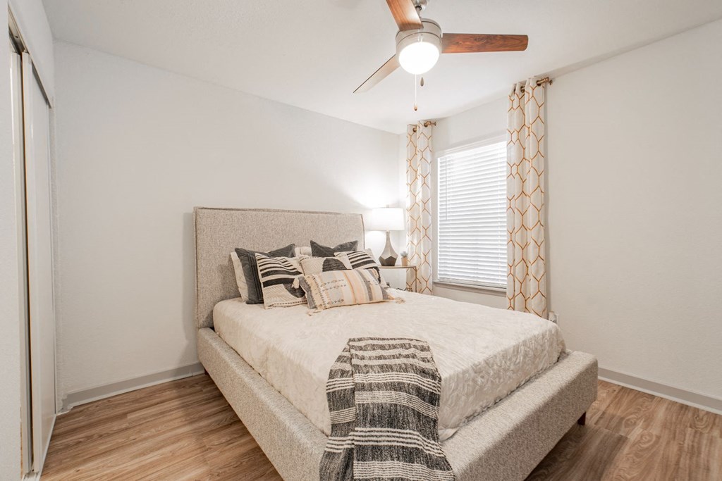 A bedroom with a bed, pillows, and a ceiling fan.