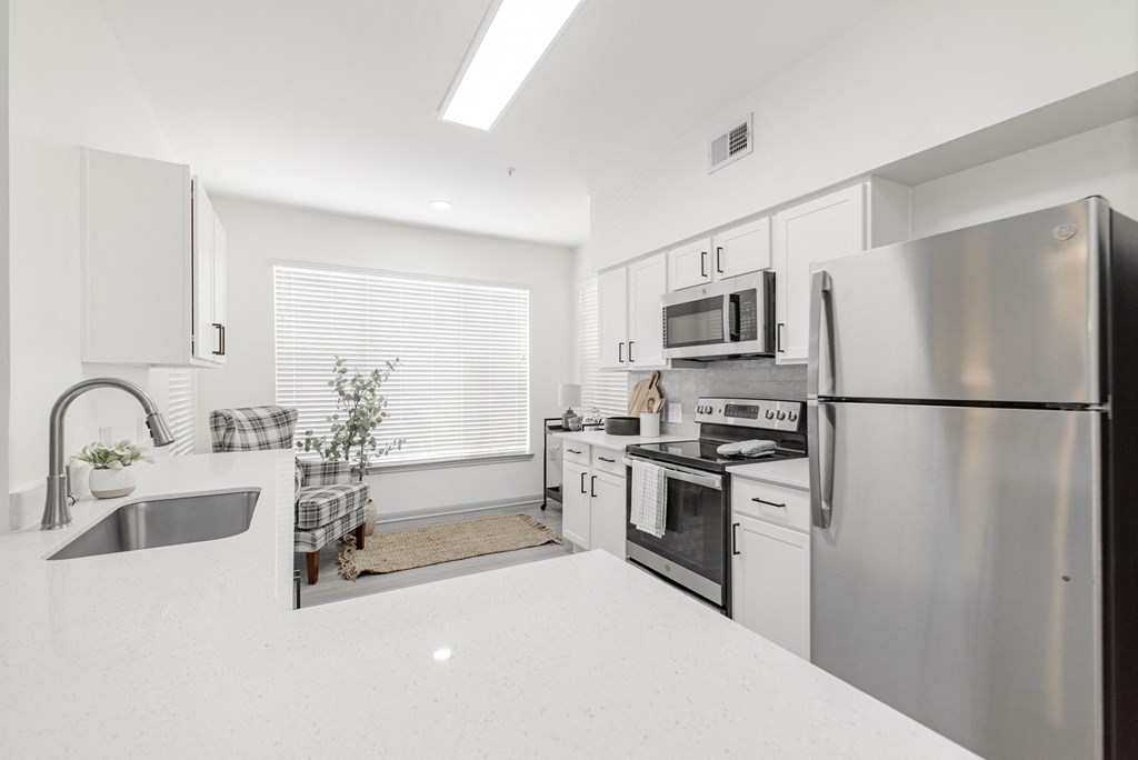 a white kitchen with stainless steel appliances and white counter tops