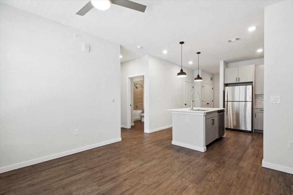 a renovated living room and kitchen with a refrigerator and a sink