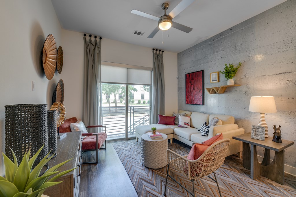 A living room with a sofa, chairs, and a ceiling fan.
