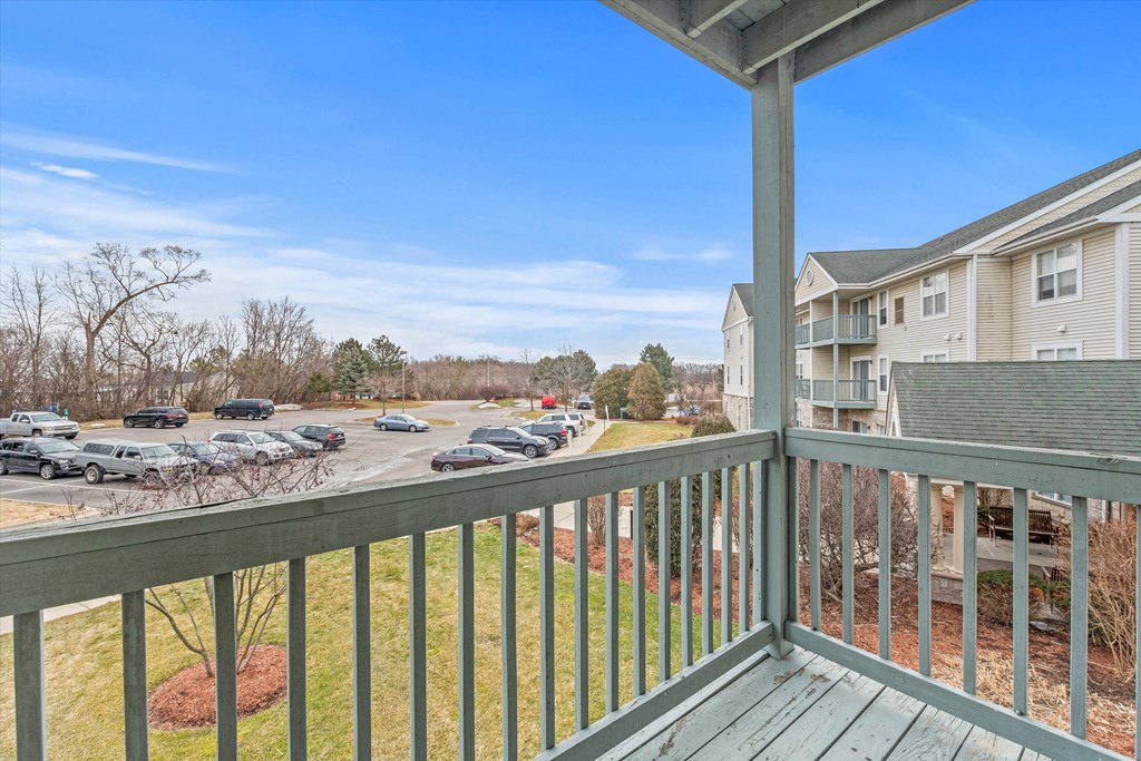 the view from the deck of an apartment building with a parking lot