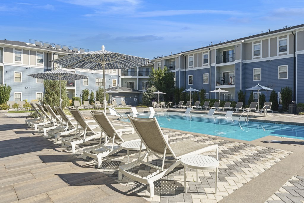 A row of sun loungers are set up by a pool.