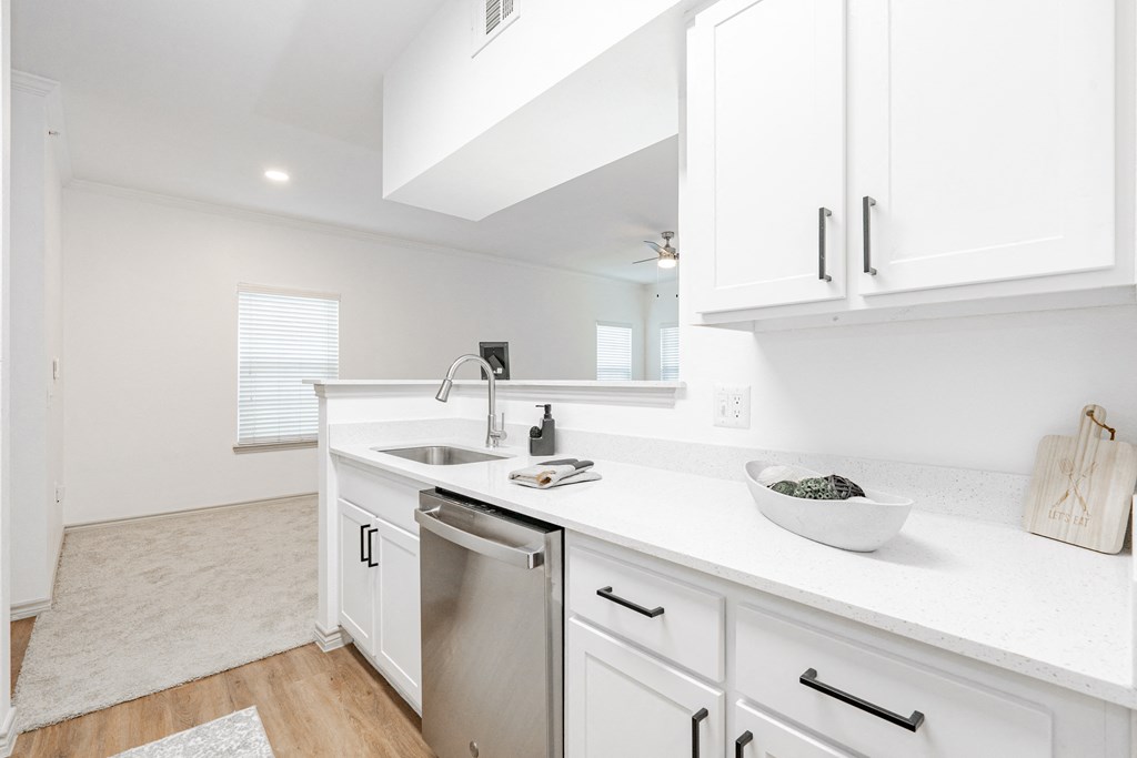 a white kitchen with white cabinets and a stainless steel dishwasher