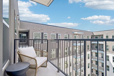 A balcony with a chair and table overlooking a building.