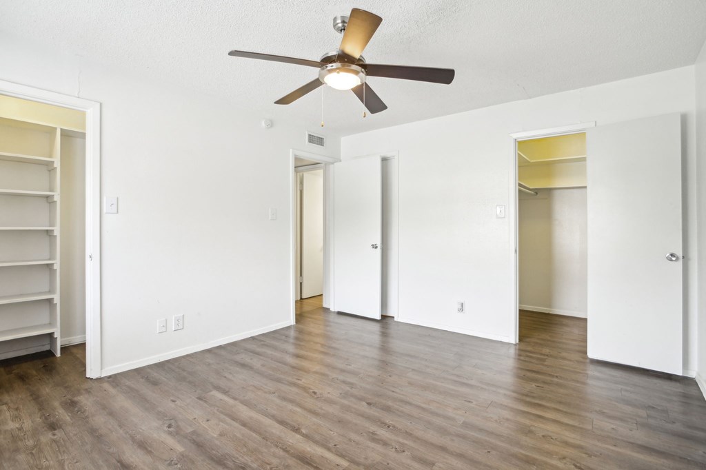 A room with a ceiling fan and wooden flooring.