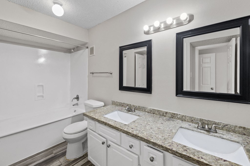 A bathroom with a toilet, sink, and mirror.