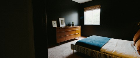 a bedroom with a bed and a dresser and a window