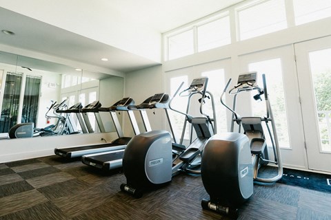 a gym with cardio equipment on the floor and windows
