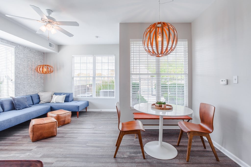 A modern living room with a blue couch and a white dining table.