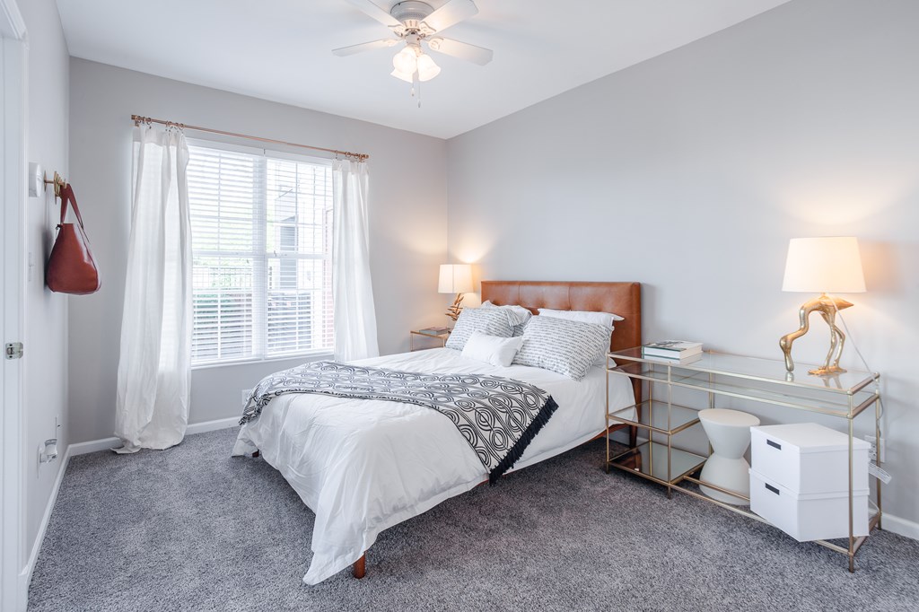 A bedroom with a bed, nightstand, and window.
